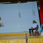 Miss Lillian instructs the students on debate topic in the Dynamo Theatre production INCOTROL Reloaded